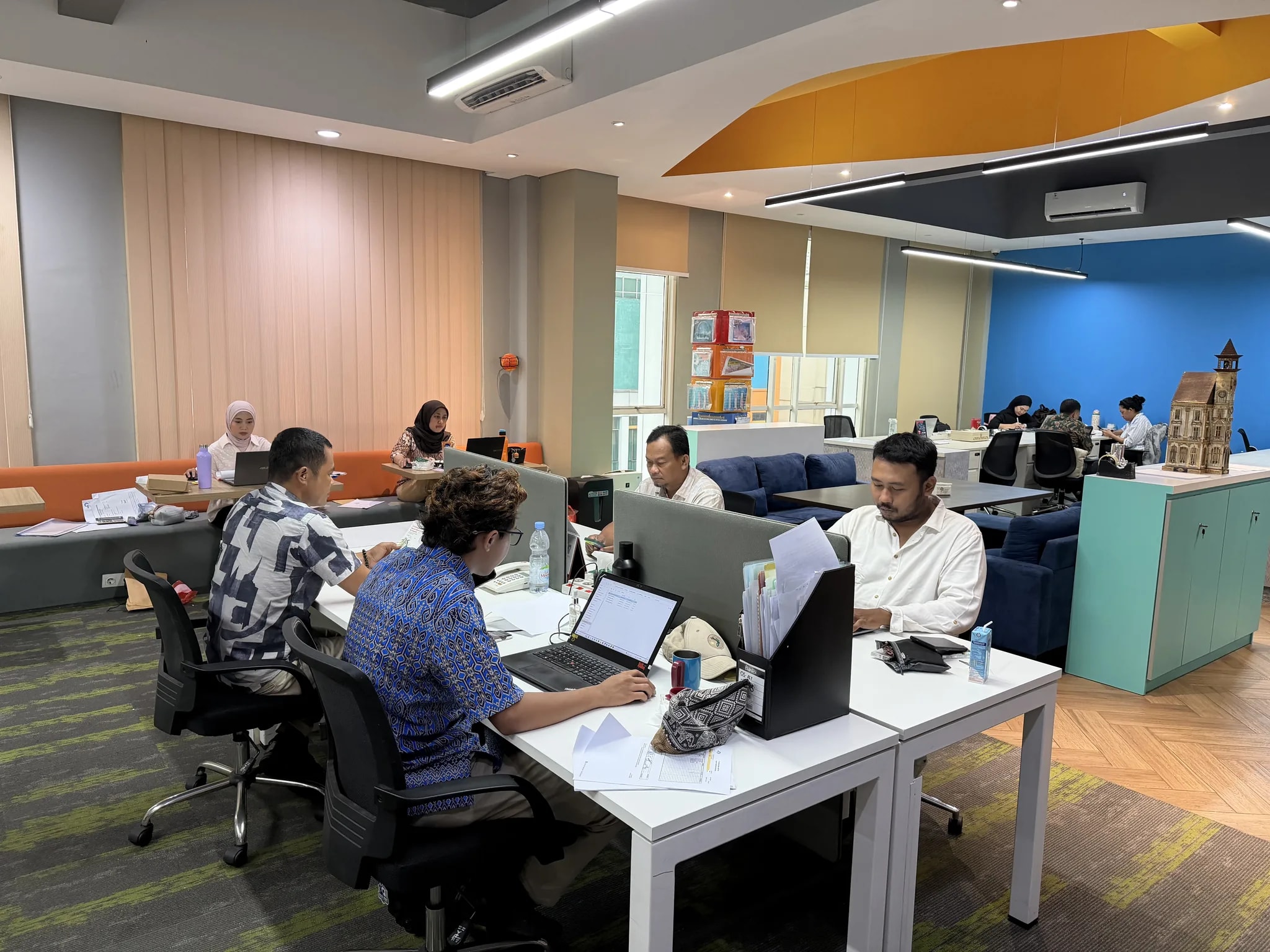 The MODA Holdings team collaborating at their desks in the open-plan workspace.
